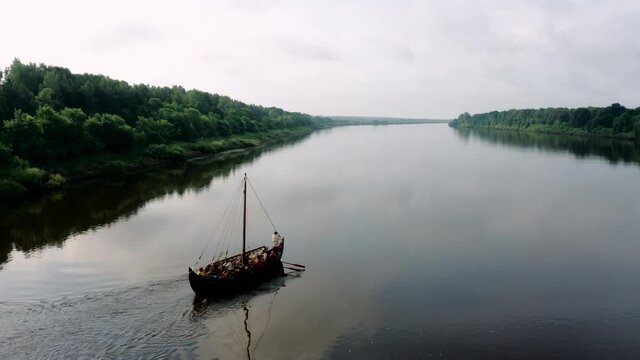 the Vikings sail on a boat along the river, beautiful forests along the banks
