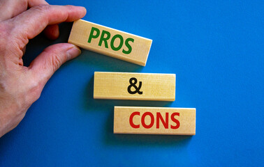 Pros and cons symbol. Wooden blocks with words 'Pros and cons'. Beautiful blue background, businessman hand. Business, pros and cons concept, copy space.