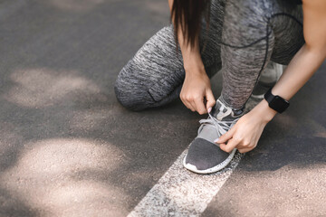 Female athlete tying sports shoes during morning jogging outdoors