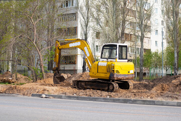 Yellow crawler excavator excavating at a construction site. Backhoe loader for foundation work and road construction. Heavy machinery and construction equipment.