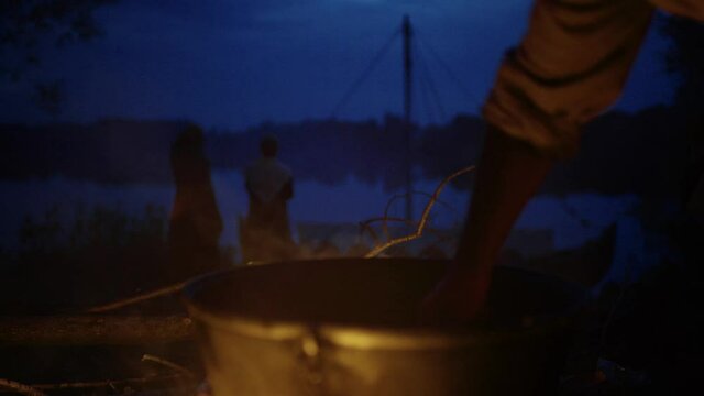 reenactors on a hike carry a cauldron for food