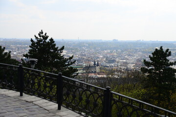 Fototapeta premium LVIV, UKRAINE - APRIL 17, 2019: People tourists at the top of High Castle Hill, Ukrainian city old town mountain peak on sunny summer day cityscape. Lviv city seen from mount on High Castle Hill