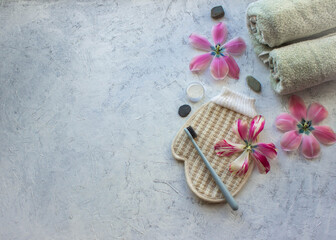 Fototapeta na wymiar bamboo toothbrush, massage washcloth, two towels lying on a gray background, environmental minmmalism
