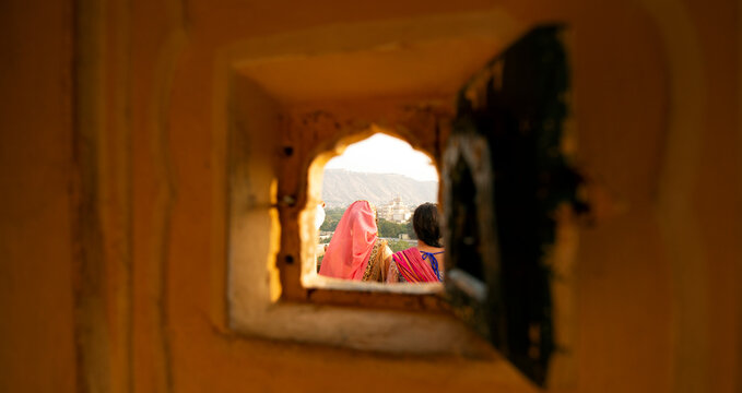 Two Indian girls wearing the traditional Indian dress 'Saree' or &acirc;&euro;&tilde;Sari&acirc;&euro;&trade; are enjoying the landscape of Jaipur from the Hawa Mahal during the Covid-19 pandemic. Jaipur, India.