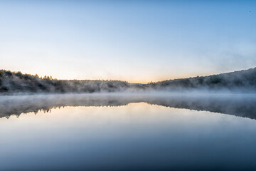 Fototapeta premium Spruce Knob Lake blue water in West Virginia at sunrise with yellow sunlight, nobody and landscape view of forest trees in autumn fall season