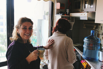 senior friends / family reunion indoors at home kitchen smiling 
