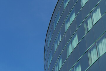 Nowoczesny budynek z szklaną ścianą na tle niebieskiego nieba, Wrocław, Polska