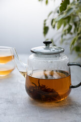 Chinese flower tea brewed in a transparent teapot with two cups .