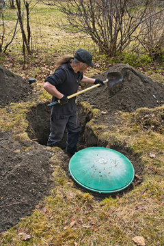 Man digging up home septic tank with a shovel