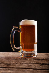 Pouring a glass of brown beer on a rough wooden table