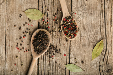 Mix of peppers in spoon on wooden background top view