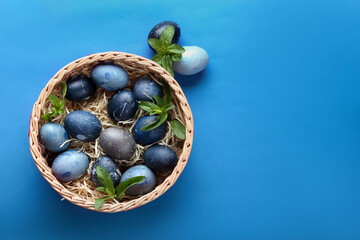 Blue eggs in a basket and mint on a blue background top view
