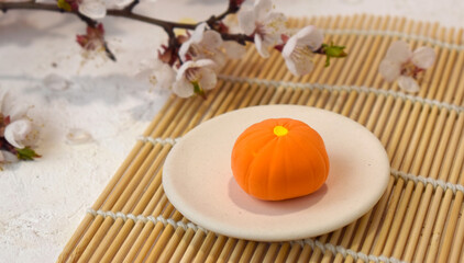 Close up Japanese traditional confectionery mochi with blossom on bamboo mat. Healthy vegan rice sweets. Beautiful wagashi.  Concept for restaurant menu, receipt instruction.