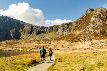 Group of hiking backpackers in Welsh mountains walking next to the lake Llyn Idwal.