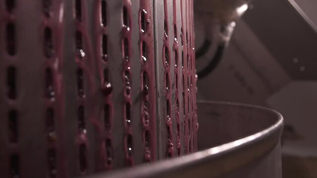 Grape juice exit modern mechanical stainless steel wine press after extraction. Wine press expel pressed fermented grapes in a wine factory. Close up, slow motion.