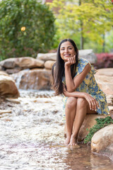 Beautiful Asian Indian woman sitting by a small creek