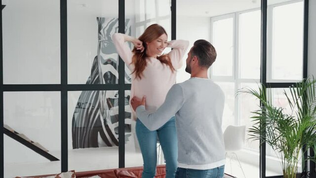 Beautiful Young Heterosexual Couple Having Fun And Dancing At Home Together