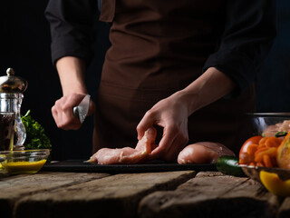Cooking chicken fillet. The chef cuts and prepares poultry meat. Homemade food, wholesome food, organic food. Restaurant dish. A hearty lunch. Oven-pigmented marinated chicken