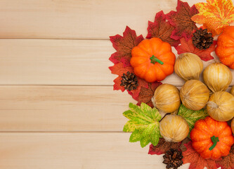 Autumn decor with pumpkins, onions, maple leaves and cones on a wooden background