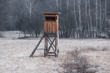 Hunting high stand on a meadow with dead grass in winter without snow