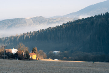 Meadow with dead grass above a town and hills in the background in the morning