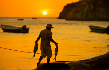 fisherman walking by the sea with catch on his hands