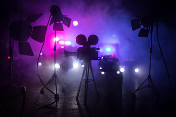 Action movie concept. Police cars and miniature movie set on dark toned background with fog. Police...