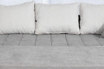 Closeup shot of a grey drape sofa with white pillows