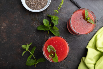 Watermelon juice with chia seeds and mint in glass on a black concrete background with green textile. Top view,  close up.