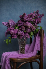 
A bouquet of lilacs on a wooden chair