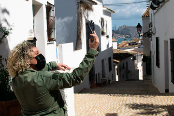blonde woman with curly hair taking a picture of a white village street