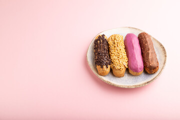 Set of eclair, traditional french dessert on ceramic plate on pink pastel background. side view, copy space.