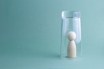The concept of loneliness, isolation of a person from society, a special person among people, autism. Wooden human image under a glass on a gray background.