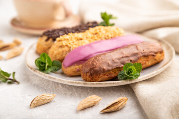 Set of eclair, traditional french dessert and cup of coffee on gray concrete background. side view, close up, selective focus.
