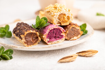 Set of eclair, traditional french dessert and cup of coffee on gray concrete background. side view, close up, selective focus.