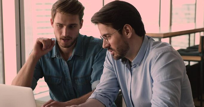 Two office manager reviewing new business application discuss corporate software use laptop, close up. At briefing colleague gives information instructions to trainee. Apprenticeship mentoring concept