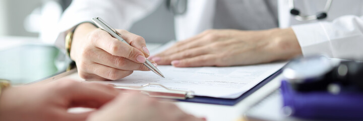 Doctor advising patient and writing in documents closeup