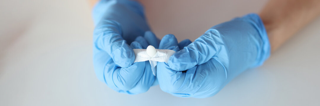 Doctors hands in rubber gloves opening rectal suppository closeup