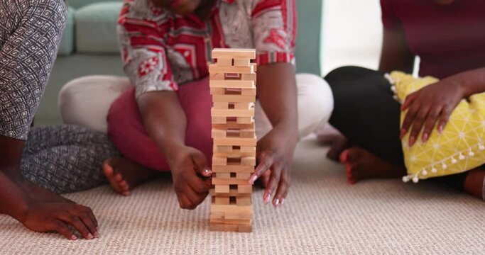 wooden block tower falling down, laughing friends playing game at home