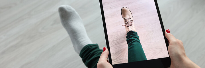 Woman holding tablet over her leg and trying on shoes closeup