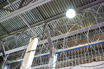 Barbed wire border. Barbed wire under hangar roof. Barbed wire for protection against intrusion. Prickly border over the partition. Protective partition inside a warehouse or hangar.