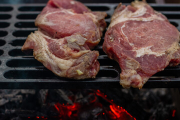 Two pork steaks are grilled on the grill. Types of burning coals