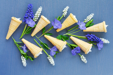 Delicious dessert in waffle cones on a blue background with spring flowers. Top view