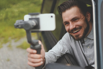 Portrait of successful man recording vlog at smartphone with steadycam