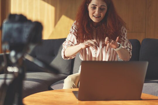 Cropped portrair of business woman recording presentation with digital camera, tripod and laptop - Powered by Adobe