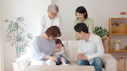 リビングでリラックスする三世代家族