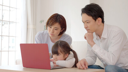 パソコンを見て考え事をする親子