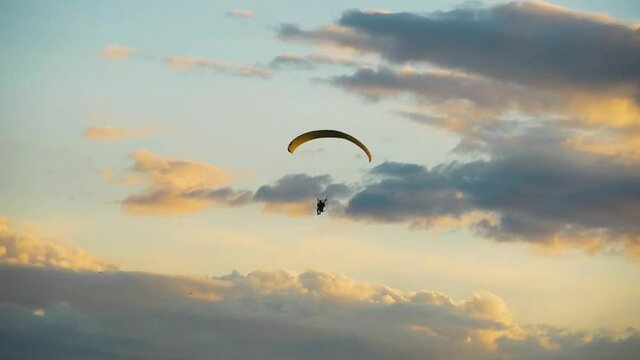 Rotor paraglider moving on warm, colorful sunset sky with clouds, in Scandinavia