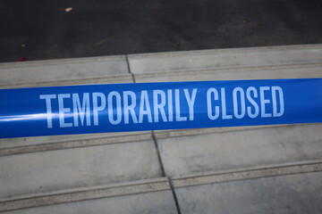 Temporarily closed caution tape. Closed due to Covid-19. Information notice sign about quarantine...