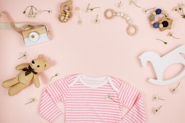 pink bodysuit, bear and accessories for newborn boy on pink table. Mockup of infant bodysuit from organic cotton with eco friendly wooden toys. Baby shower, festival, birthday decoration. Top view